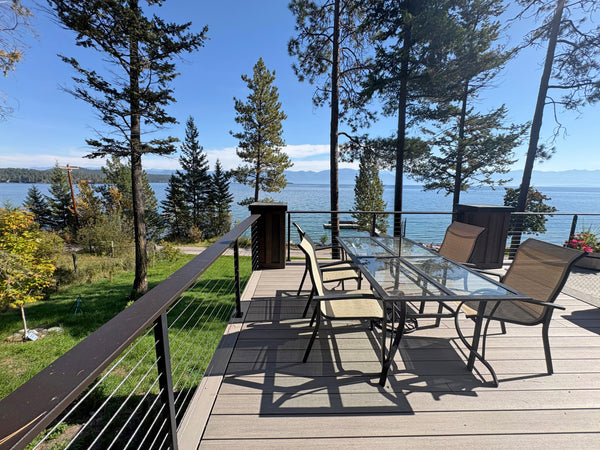 Black cable railing and outdoor dining area overlooking a waterfront view